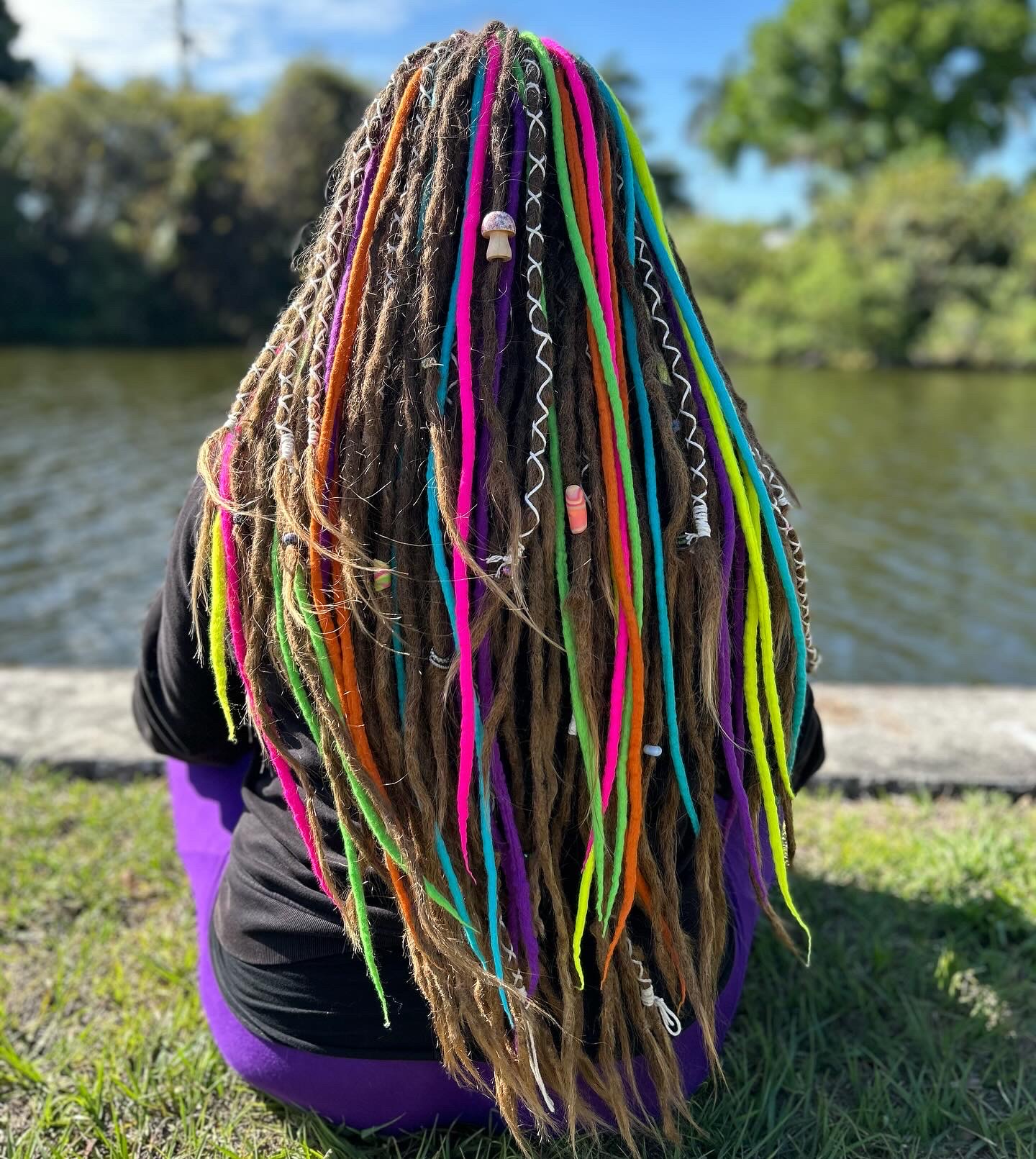 Dreadlocks decorated with rainbow woolie extensions.